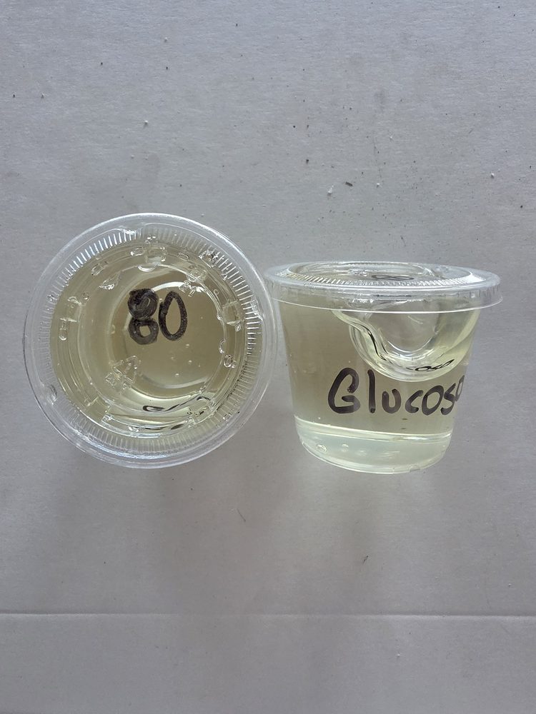 Glucosa transparente color amarillo palido en vaso plástico con tapa
