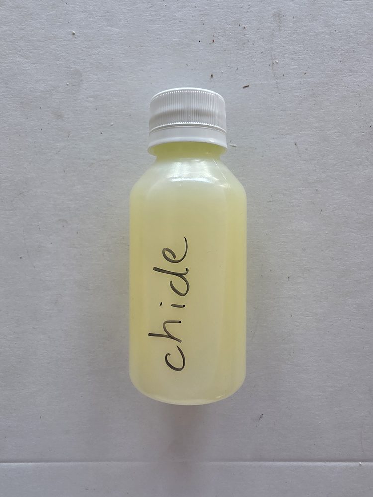 Esencia liquida color amarillo palido en frasco plástico transparente