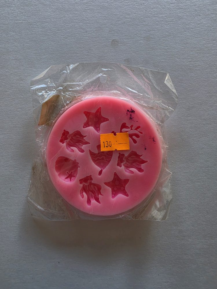 Molde de silicón rosado redondo con figuras marinas: estrellas