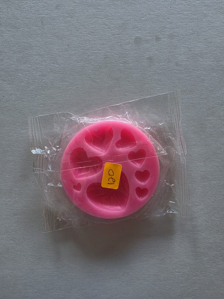 Molde de silicón rosado redondo con cavidades de corazones de varios