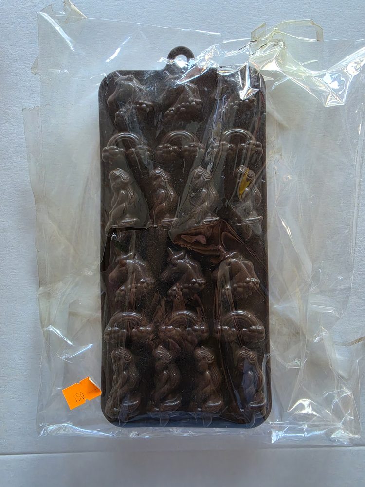 Molde rigido de plástico café oscuro para chocolates, con doce