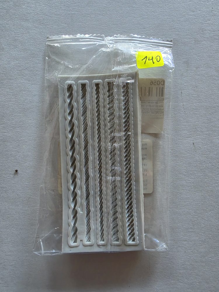 Molde blanco rectangular con cinco tiras tipo cuerda y trenza, dentro
