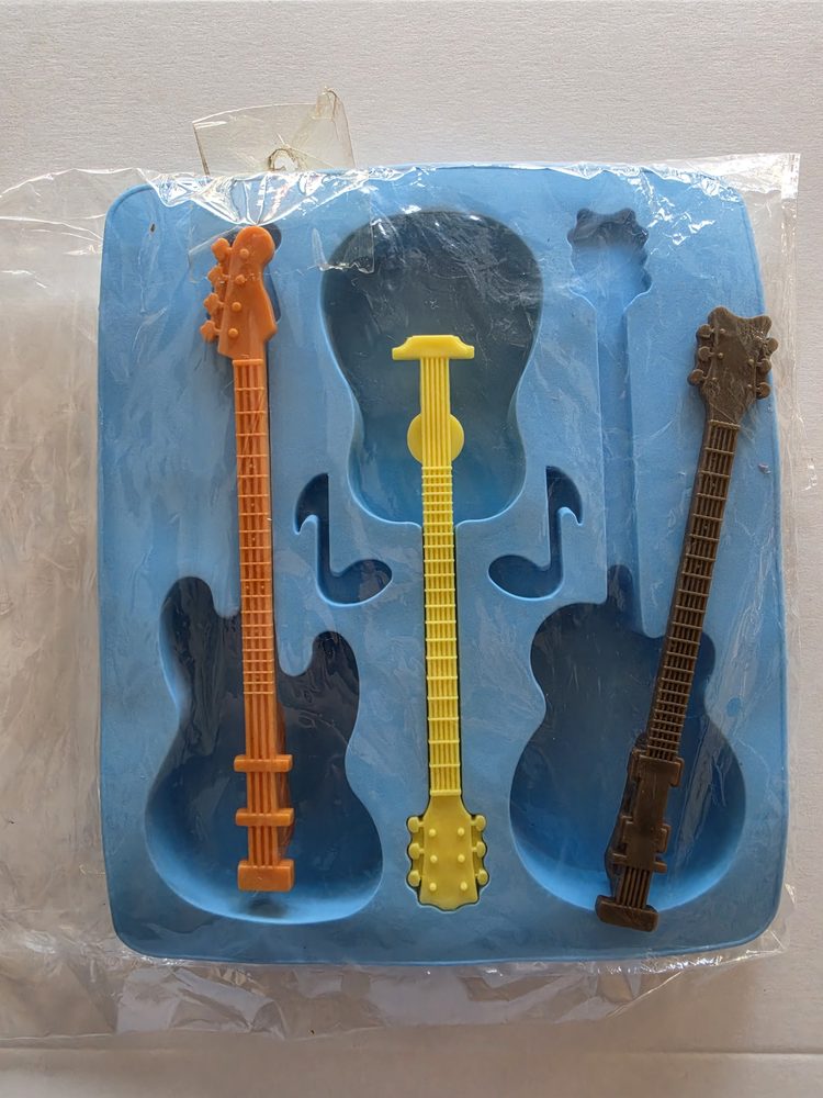 Molde de silicón azul rectangular con cavidades de guitarras