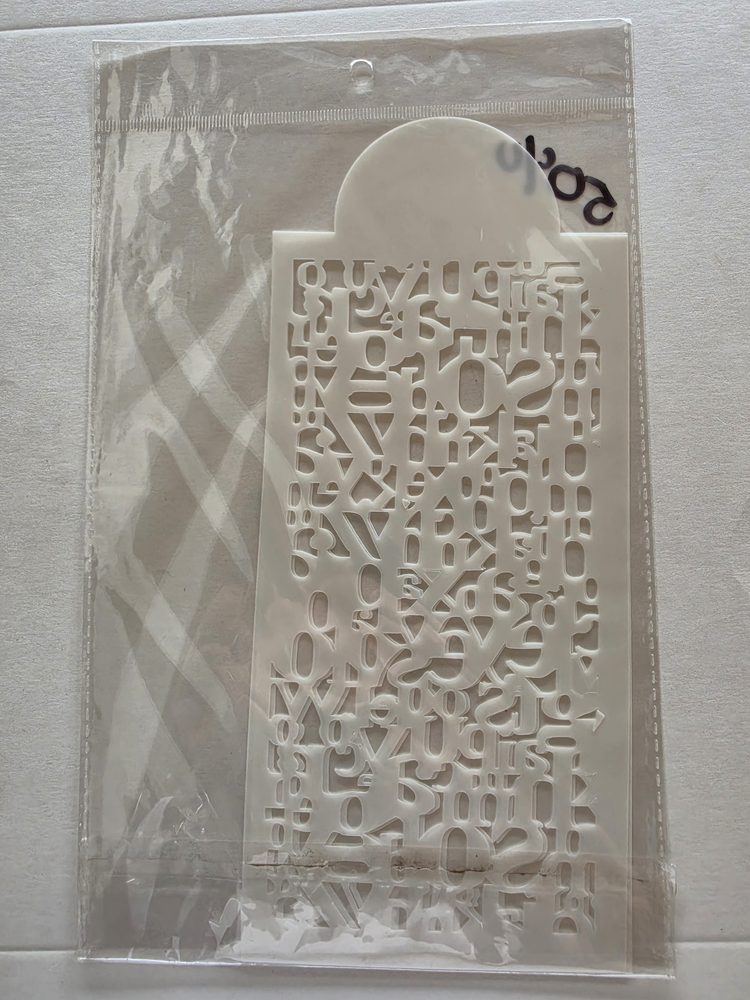 Esténcil de plástico blanco con patrón calado de letras y números